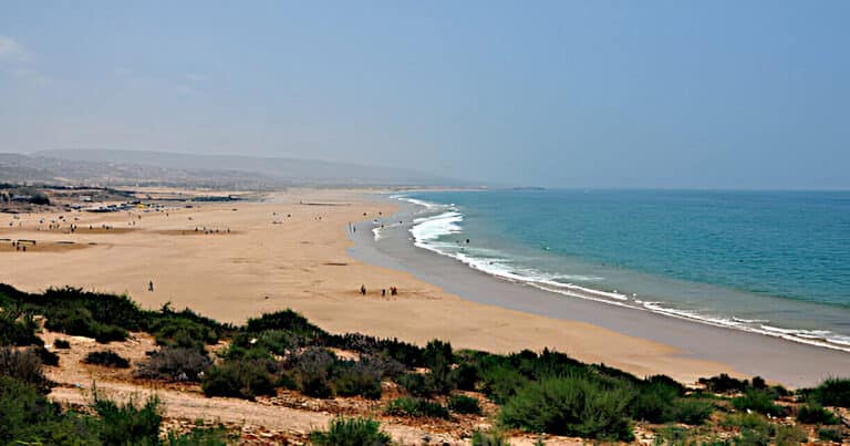 A panoramic view of a pristine beach in Morocco, showcasing the stunning coastline and inviting waters